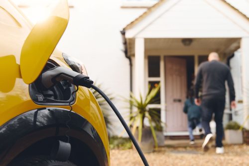 A car at an electric vehicle charging point outside a cottage